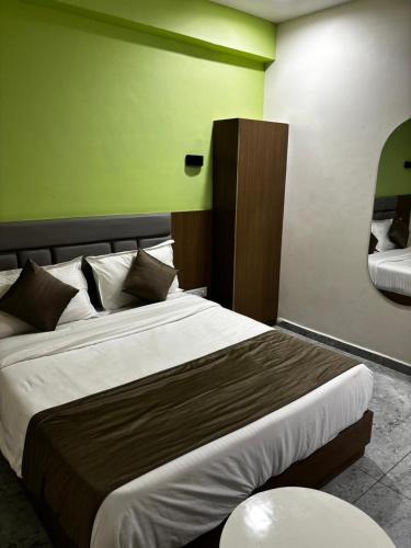 Un dormitorio con una cama grande con una pared verde. en Shiv hotel, en Ahmedabad