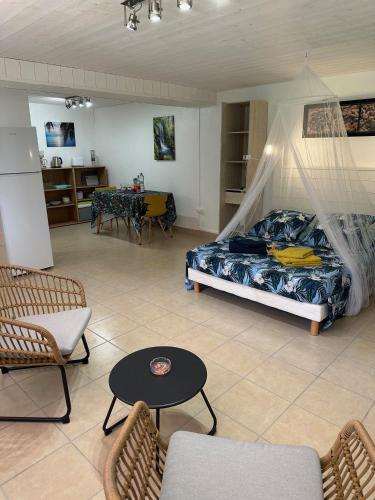 a bedroom with a bed and a table and chairs at Le Figuier De Barbarie in Sainte-Rose
