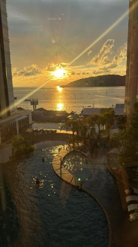 a view of a pool at a resort with the sunset at The Shore Kota Kinabalu by Ems Executive Suites Seaview in Kota Kinabalu