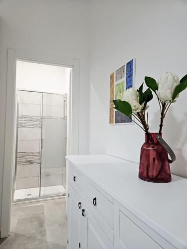 a white bathroom with a vase with flowers in it at Le Arcada - Appartamenti nel cuore del centro storico di Orosei in Orosei