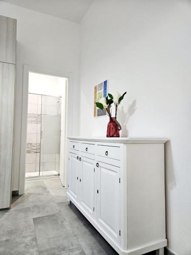 a white cabinet with a vase on it in a room at Le Arcada - Appartamenti nel cuore del centro storico di Orosei in Orosei