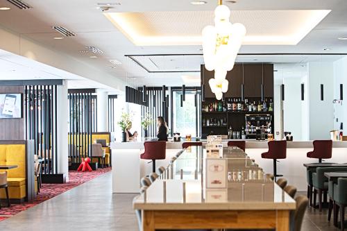 a restaurant with a long table and a bar at OSKO Hôtel Toulouse Aéroport in Blagnac