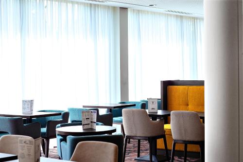 a dining room with tables and chairs and windows at OSKO Hôtel Toulouse Aéroport in Blagnac