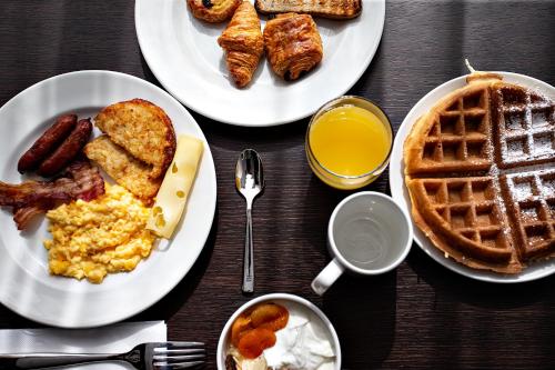 a table topped with plates of breakfast food and waffles at OSKO Hôtel Toulouse Aéroport in Blagnac