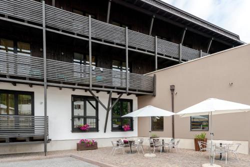 two tables and chairs with umbrellas in front of a building at Hotel Dolomiti Chalet in Vason