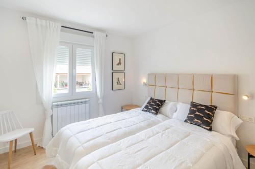 a white bedroom with a large bed and a window at Acogedora casa para familias a 15 min de Bardenas in Fustiñana
