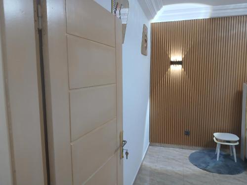 eine Tür, die in einen Flur mit einem Hocker führt in der Unterkunft Residence KLYC1 Abidjan Cocody in Abidjan