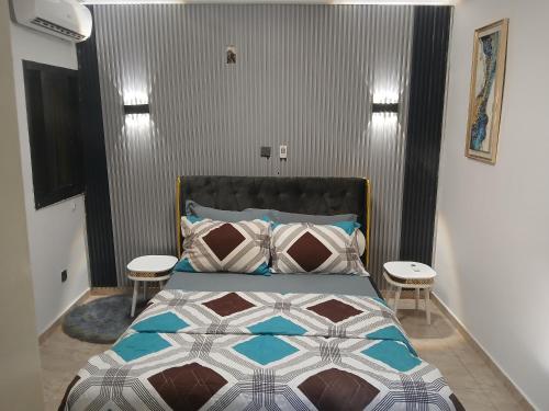 ein Schlafzimmer mit einem großen Bett mit zwei Tischen in der Unterkunft Residence KLYC1 Abidjan Cocody in Abidjan