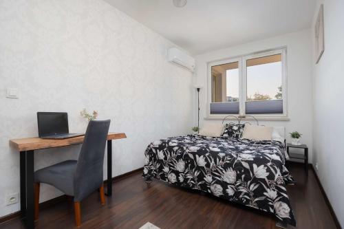Un dormitorio con una cama y un escritorio con una computadora portátil. en Stylowy Apartament w Warszawie Sypialnia & Parking w Garażu by Noclegi Renters, en Varsovia