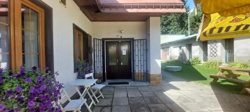 a front door of a house with benches and purple flowers at Penzion pod Severákem in Lučany nad Nisou