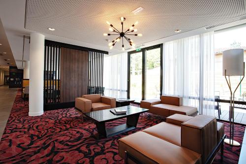 a lobby with couches and a table and chairs at OSKO Hôtel Toulouse Aéroport in Blagnac