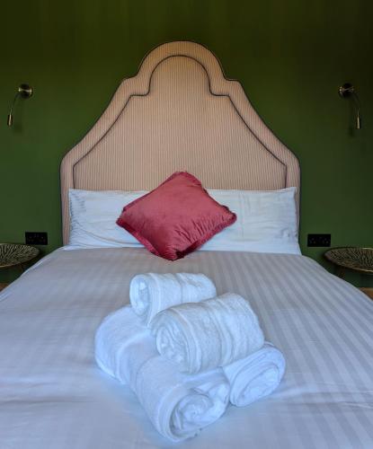 a pile of towels on a bed with a red pillow at Wonderland Berwick 5-bedrooms Pet-friendly cottage with the Hot tub in Tweedmouth