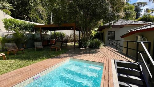 una piscina in un cortile con terrazza in legno di Casa 23 Floresta Boa Vista - 4 Suítes e Piscina Aquecida em Meio à Natureza a Teresópolis