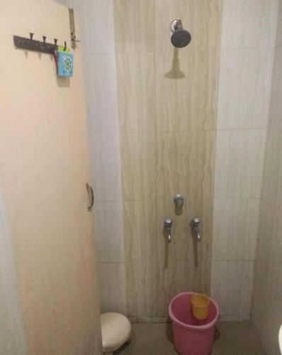 a bathroom with a shower with a toilet and a bucket at Dhanush Guest House in Kedārnāth