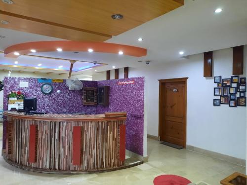 a lobby with a counter and a purple wall at Hotel Samah in Mānsehra