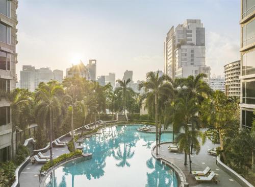 an aerial view of a pool with palm trees and buildings at Conrad Bangkok in Bangkok
