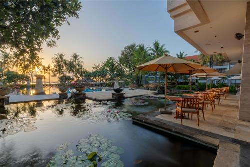 a pool at a resort with tables and chairs and lilies in the water at Conrad Bali in Nusa Dua