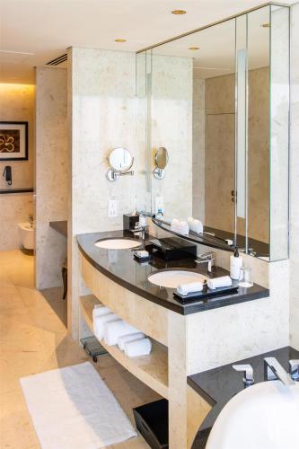 a bathroom with two sinks and a large mirror at Conrad Dubai in Dubai