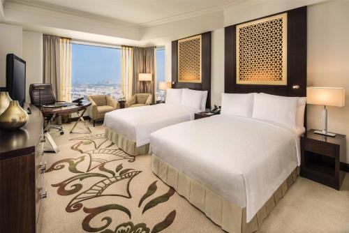 a hotel room with two beds and a desk at Conrad Dubai in Dubai