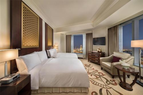 a bedroom with a large bed and a large window at Conrad Dubai in Dubai