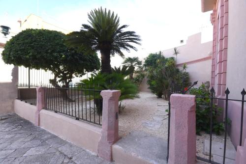 a fence with a palm tree in front of a building at Palazzo Castriota in Alezio