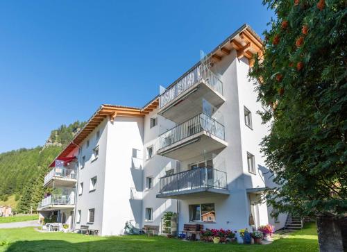 ein weißes Apartmenthaus mit Balkon und einem Baum in der Unterkunft Ferienwohnung Mengelt, Splügen in Splügen