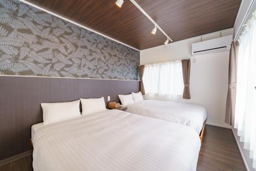 two beds in a small room with white sheets at Nagashima Onsen Villa Kuwana ,Family & Group Stay with Private Onsen in Kuwana