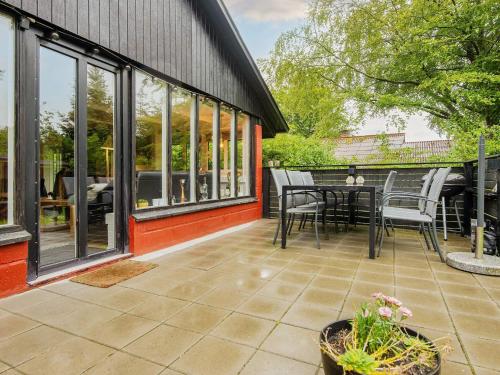 a patio with a table and chairs and windows at 6 person holiday home in Ulfborg-By Traum in Ulfborg