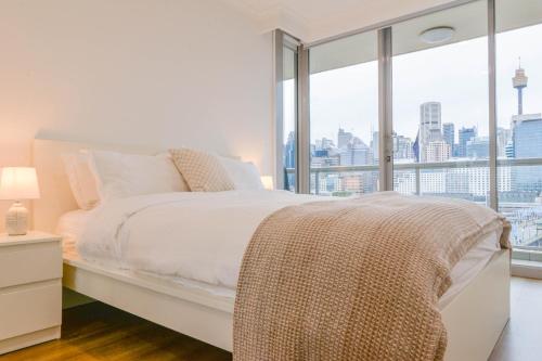ein Schlafzimmer mit einem weißen Bett und einem großen Fenster in der Unterkunft Family Harbour Escape with Harbour Views & Parking in Sydney