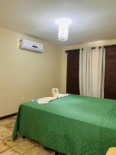 a bedroom with a bed with a green bedspread at Petit Thay Home in Cumbuco