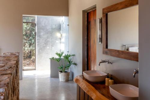 a bathroom with two sinks and a mirror at Tamodi Estate in Plettenberg Bay
