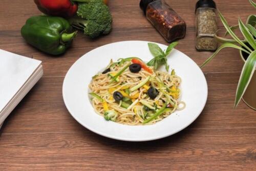 a plate of noodles with vegetables on a table at Dragonfly Hotel - The Art Hotel in Mumbai