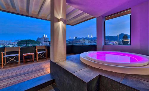 a hot tub on a balcony with a view of the city at Esplanade Tergesteo - Luxury Retreat in Montegrotto Terme