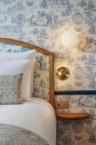 a bedroom with a bed and a wall covered in wallpaper at Hotel de Neuve by Happyculture in Paris