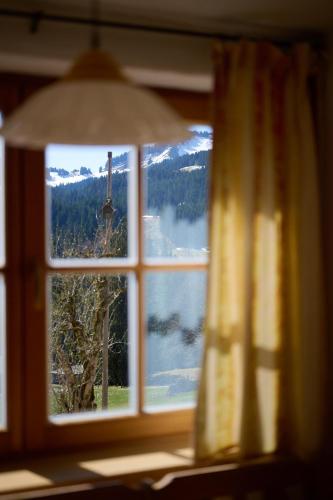 a window with a view of a lake and mountains at Ferienhof Almfrieden in Balderschwang