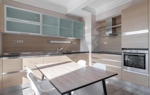 リガにあるPanorama Riga 25th Floor Spacious Apartment Free Parkingのキッチン(木製テーブル、白い椅子付)