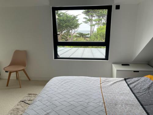 a bedroom with a window and a bed and a chair at Maison les pieds dans l'eau in Trébeurden