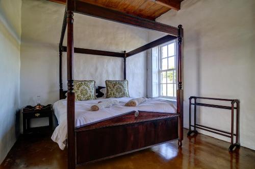 a canopy bed in a room with a window at Melkkamer Vlei Cottage in De Hoop Nature Reserve