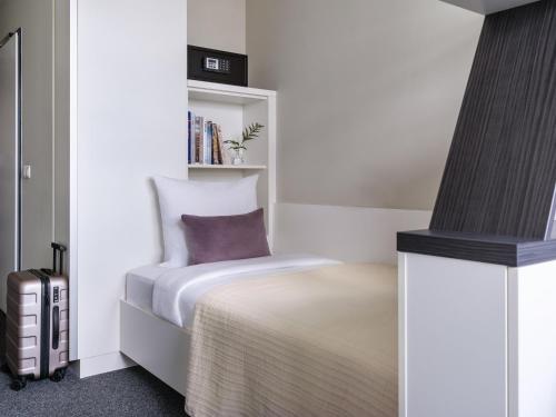 a small bedroom with a bed and a book shelf at Numa Munich Viktoria in Munich