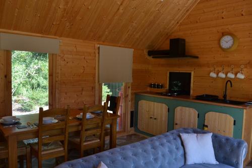 a living room with a couch and a table and a kitchen at Oak Cabin - Wild Escapes Wrenbury off grid glamping - ages 12 and over in Baddiley
