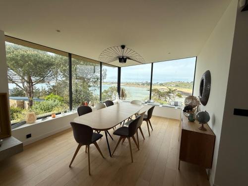 a dining room with a table and chairs and large windows at Maison les pieds dans l'eau in Trébeurden