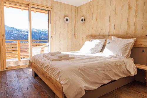 a bedroom with a large bed with a large window at La Licorne de l'Encombrette 150 m2 in Allos