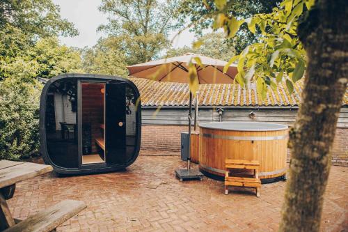 a hot tub and an umbrella next to a building at Veluwepark de Bosgraaf in Apeldoorn