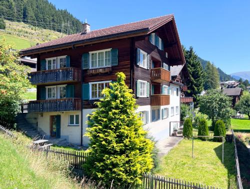 una casa de madera con un árbol delante en Ferienwohnung Bergblick, en Sedrun