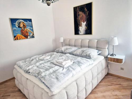 a white bed in a room with paintings on the wall at Sternhaus - Appartement am Kurpark in Bad Schallerbach