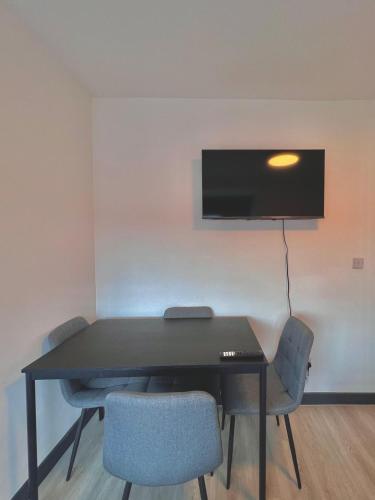 a black table with chairs and a tv on a wall at Golders Green Studios in London