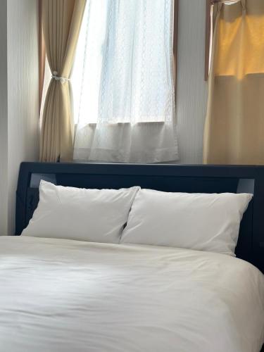 a bed with white pillows in a bedroom with a window at 淺夏館Asakakan2 in Tokyo