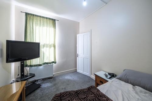 a bedroom with a bed and a flat screen tv at House - Sleeps 8 - Garden - Short Walk to Station in London
