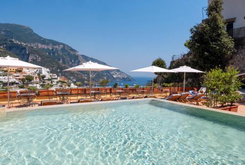 a swimming pool with tables and chairs and umbrellas at Hotel Posa Posa in Positano