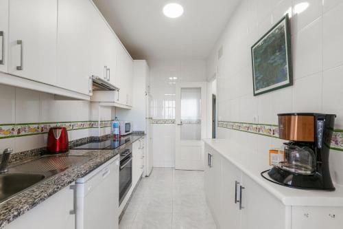 a kitchen with white cabinets and a sink at SUENO by the Sea in Dehesa de Campoamor